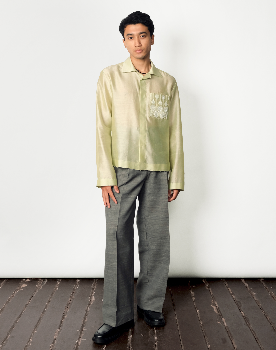 Pale green relaxed Chanderi silk shirt featuring hand embroidered logo-inspired pocket and glass bead trim by Taarini Anand