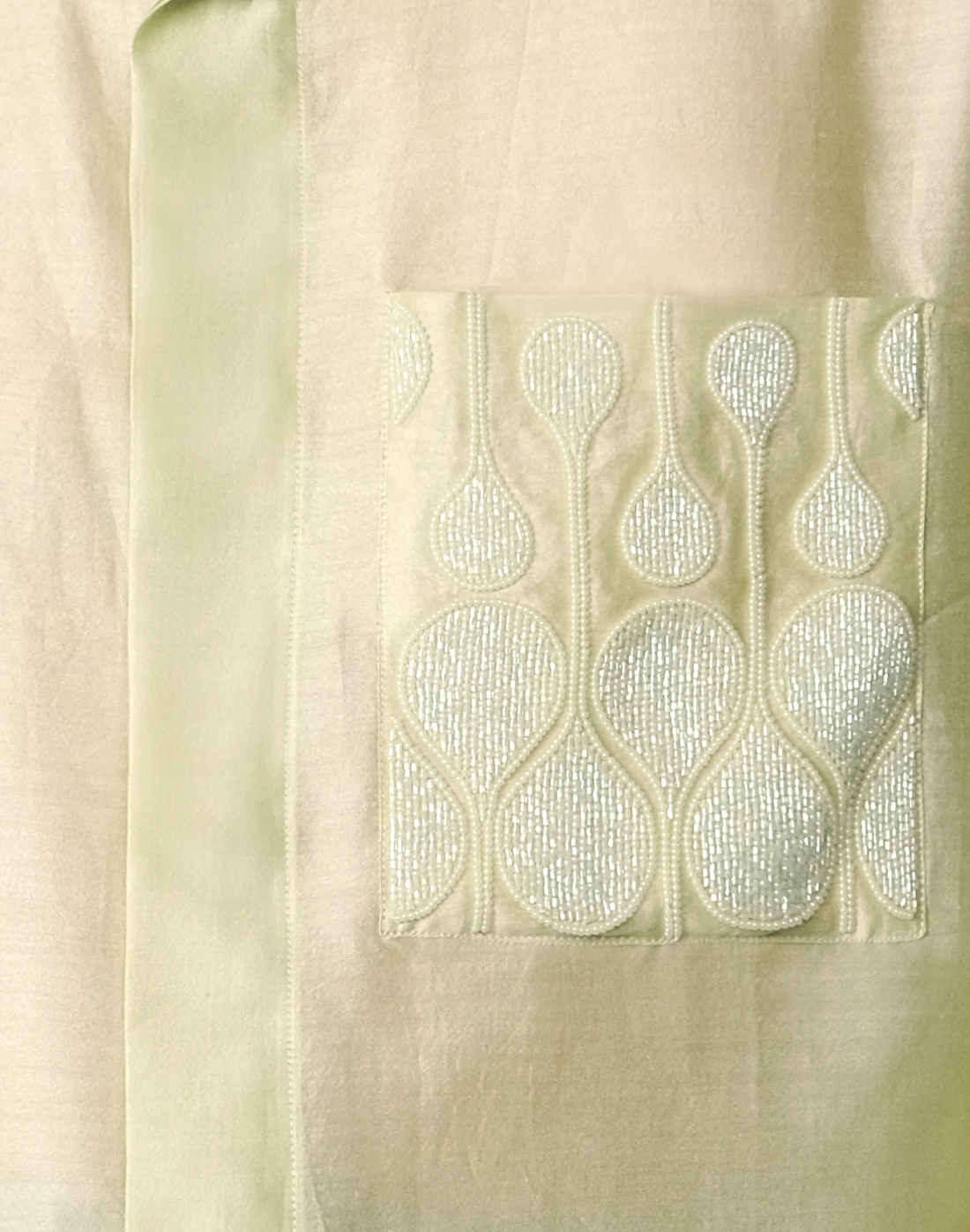 Pale green relaxed Chanderi silk shirt featuring hand embroidered logo-inspired pocket and glass bead trim by Taarini Anand pocket