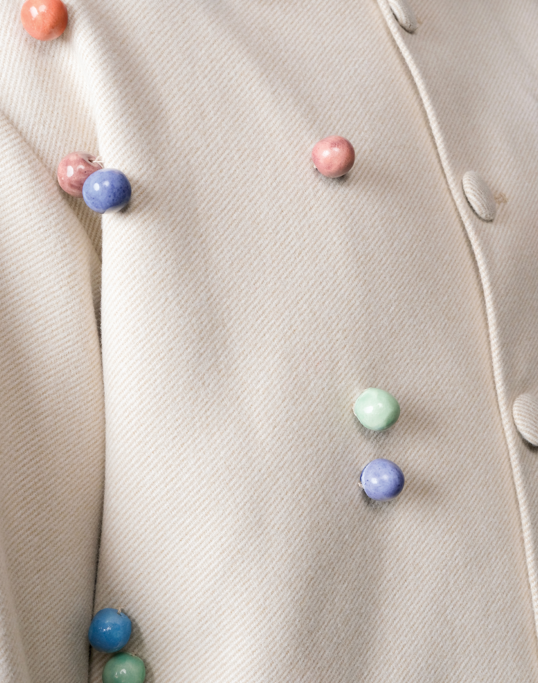 Artisanal wool twill jacket in beige with colourful handmade ceramic beads by Taarini Anand close up
