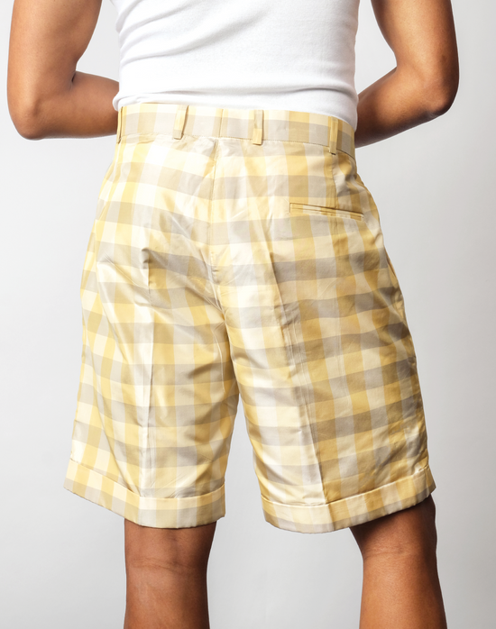 Back view of handwoven silk gingham taffeta pleated shorts, in a green and yellow check pattern.