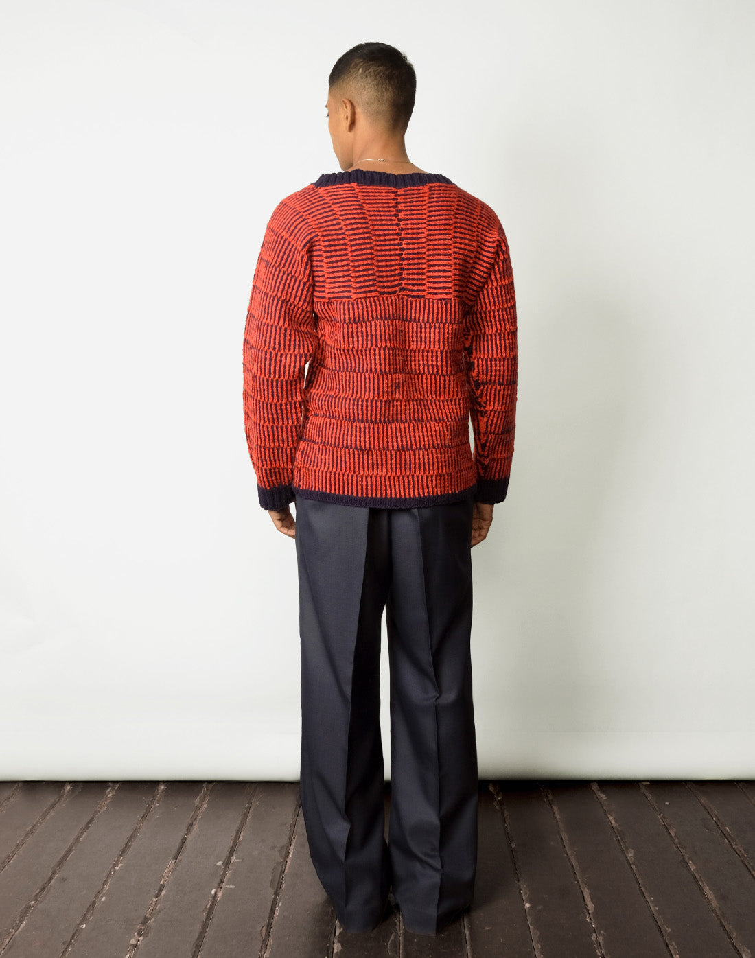 back view red and navy striped kimono-cut sweater with a boat neckline and wide leg navy trousers.