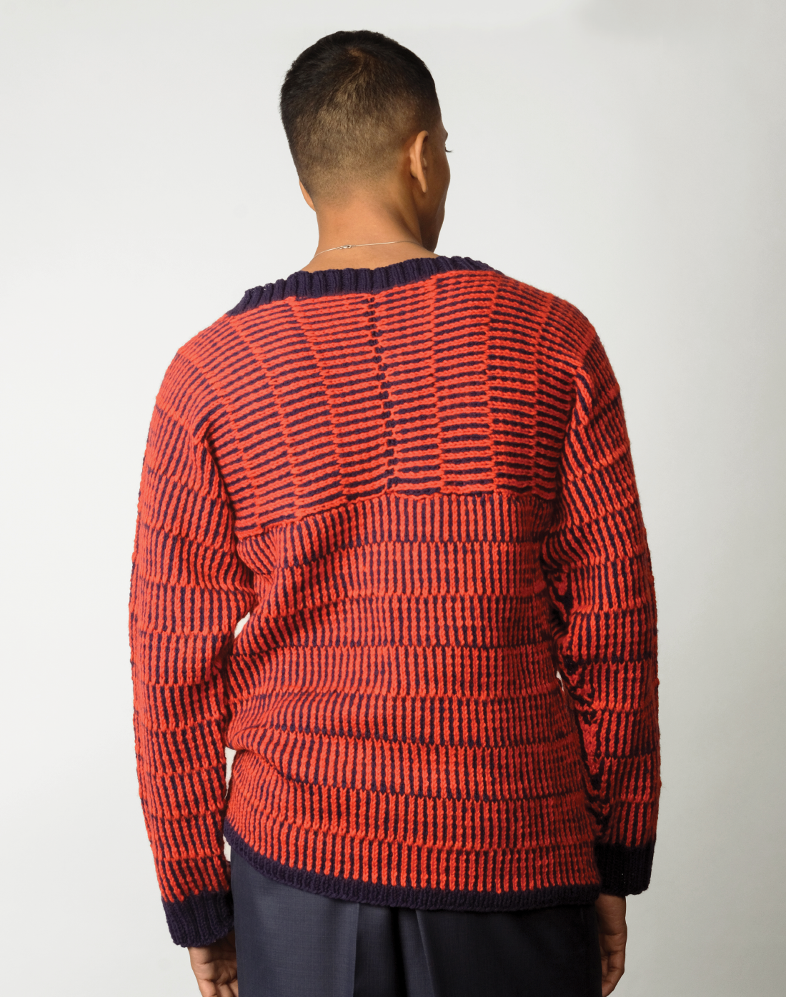 back view red and navy striped kimono-cut sweater with a boat neckline and wide leg navy trousers.
