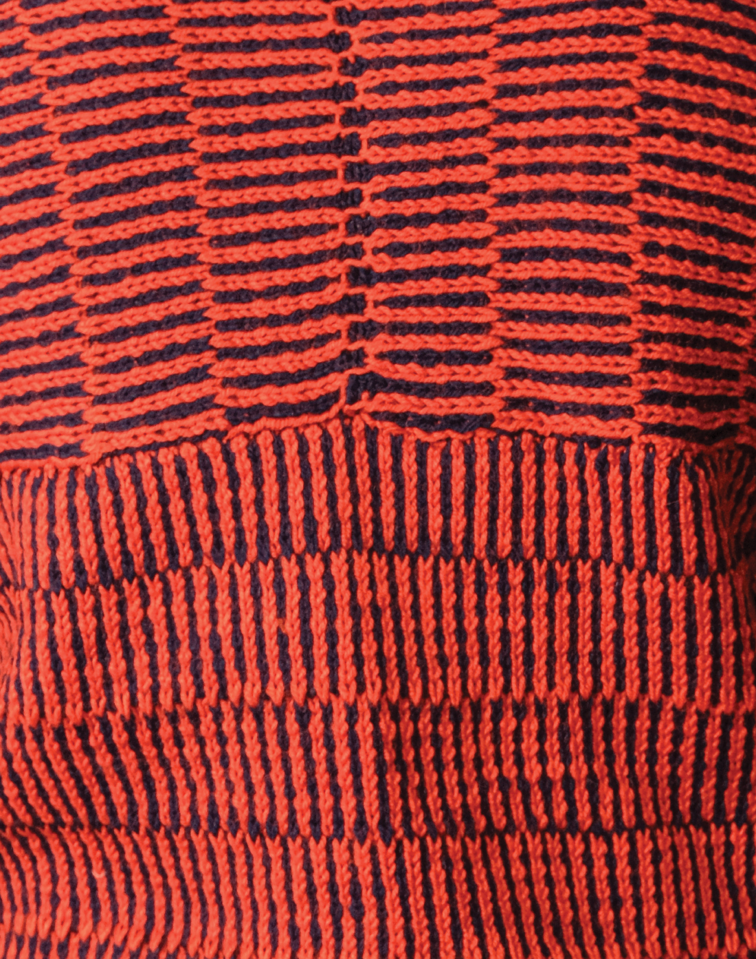 close up red and navy striped kimono-cut sweater with a boat neckline and wide leg navy trousers.