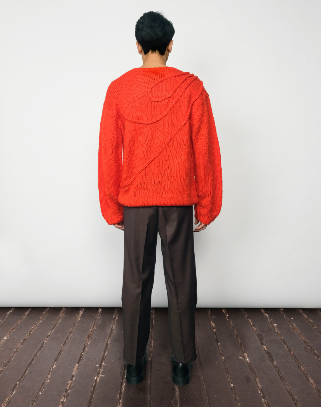 Bright red hand-knit Inferno Sweater styled with black Double Box Pleat Trousers by Taarini Anand