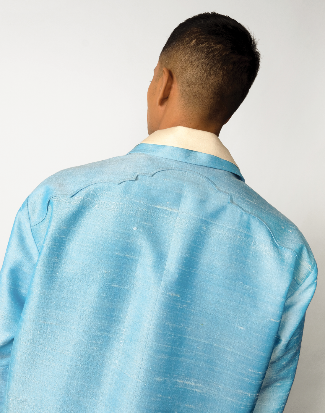 Sky blue raw silk jacket with dropped shoulders, arch-shaped yokes, and four patch pockets arch