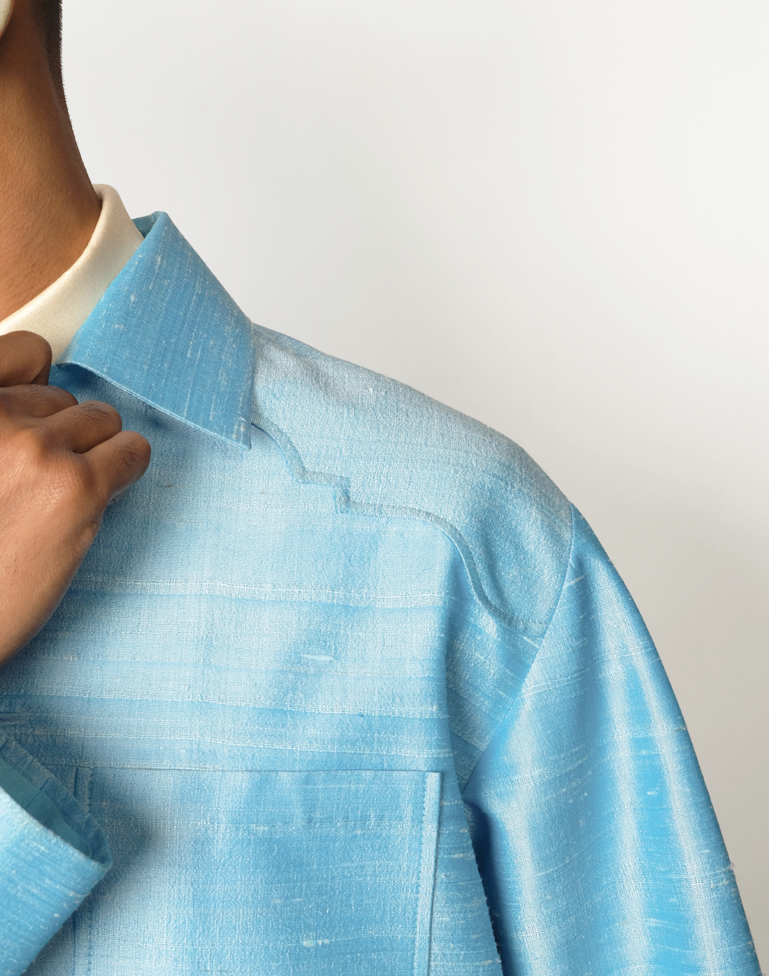 Sky blue raw silk jacket with dropped shoulders, arch-shaped yokes, and four patch pockets close up